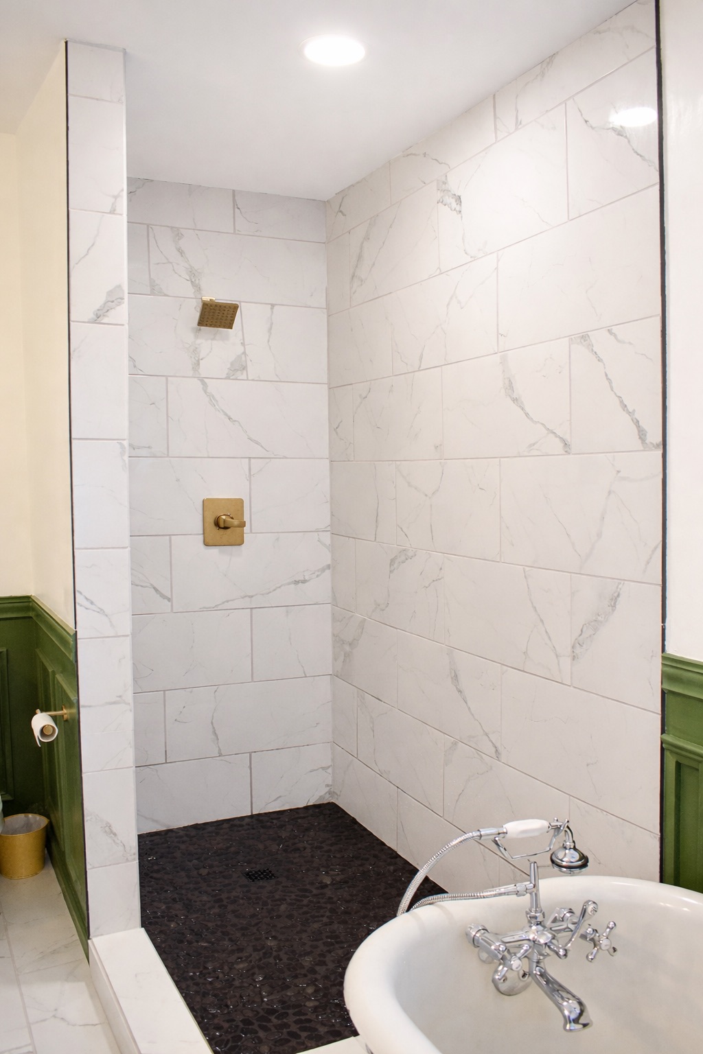 Marble walk-in shower with brass fixtures and pebble floor