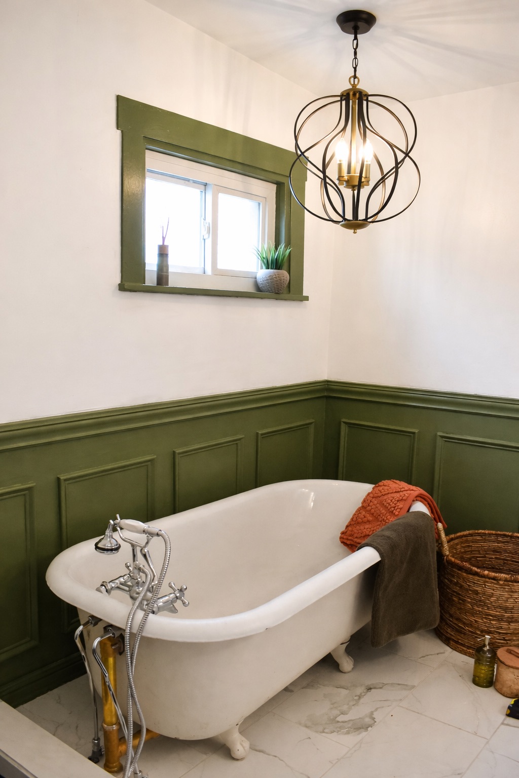 Clawfoot tub bathroom with sage wainscoting and orb chandelier